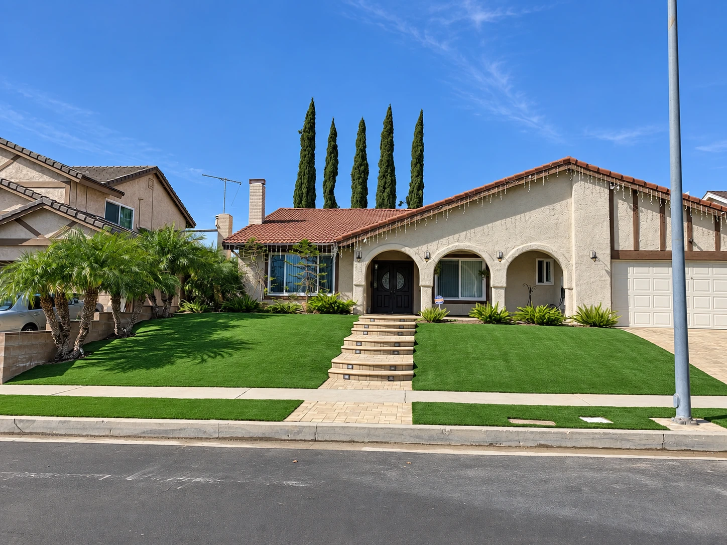 A front lawn framed by planting and a stone walkway